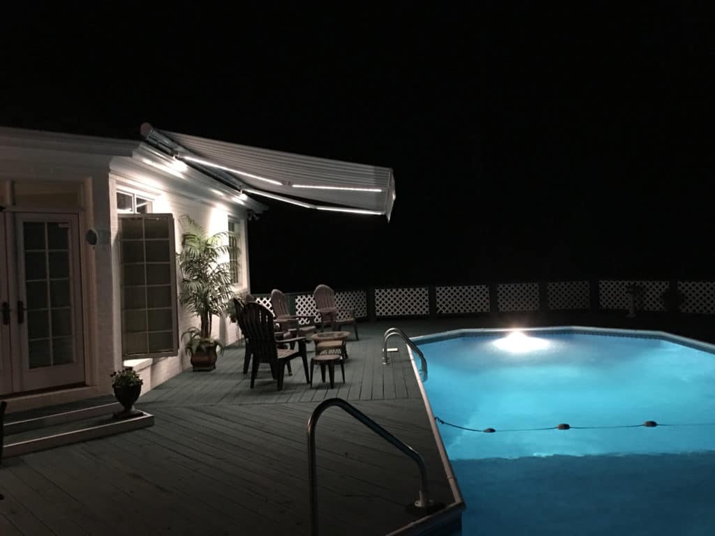 Swimming pool at night with LED lit awning over the patio
