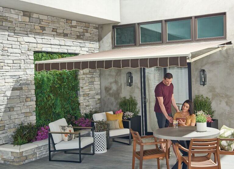 Man and woman looking at iPad on outside patio under awning